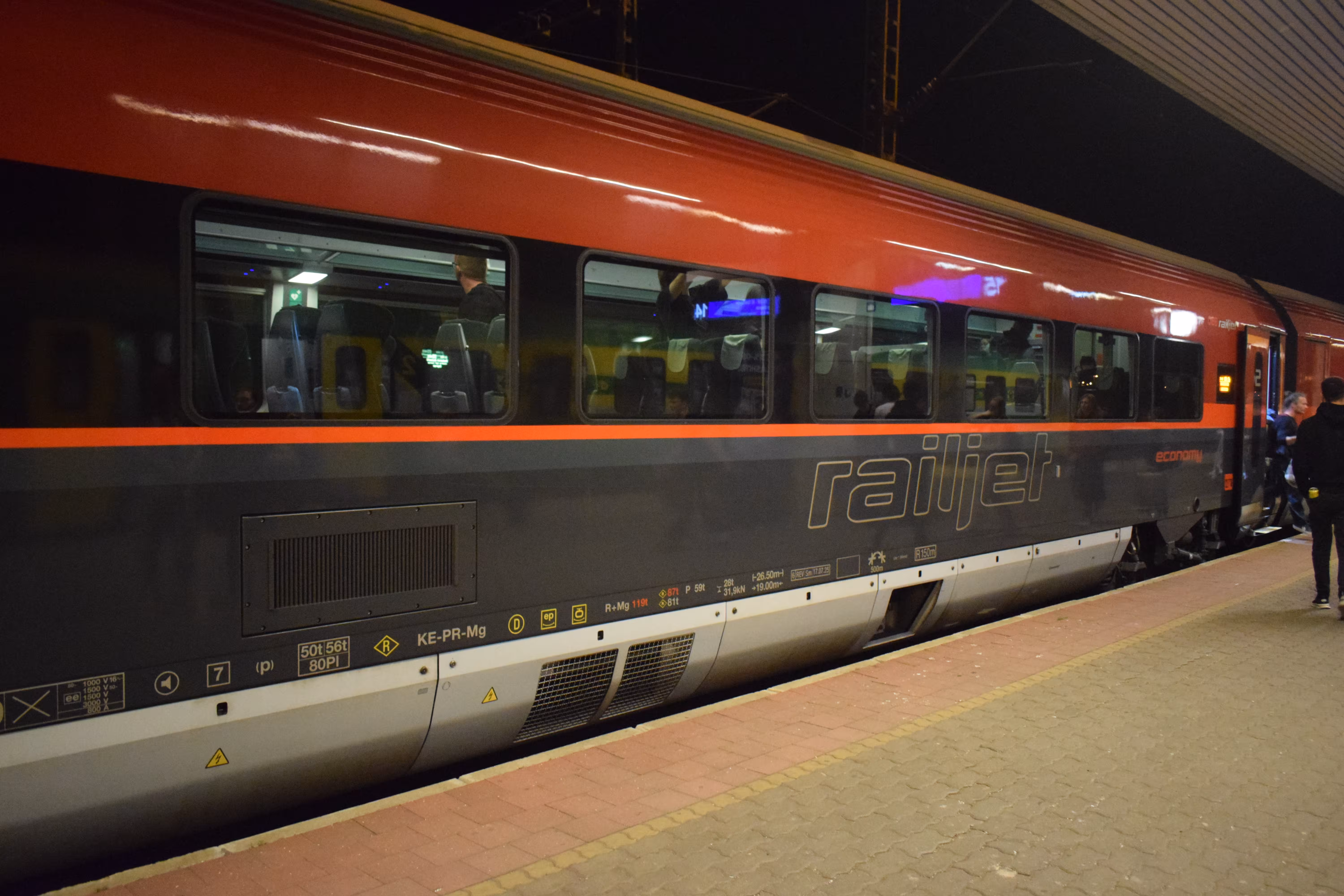 A red colored train standing on the platform of Budapest Kelenfold station.