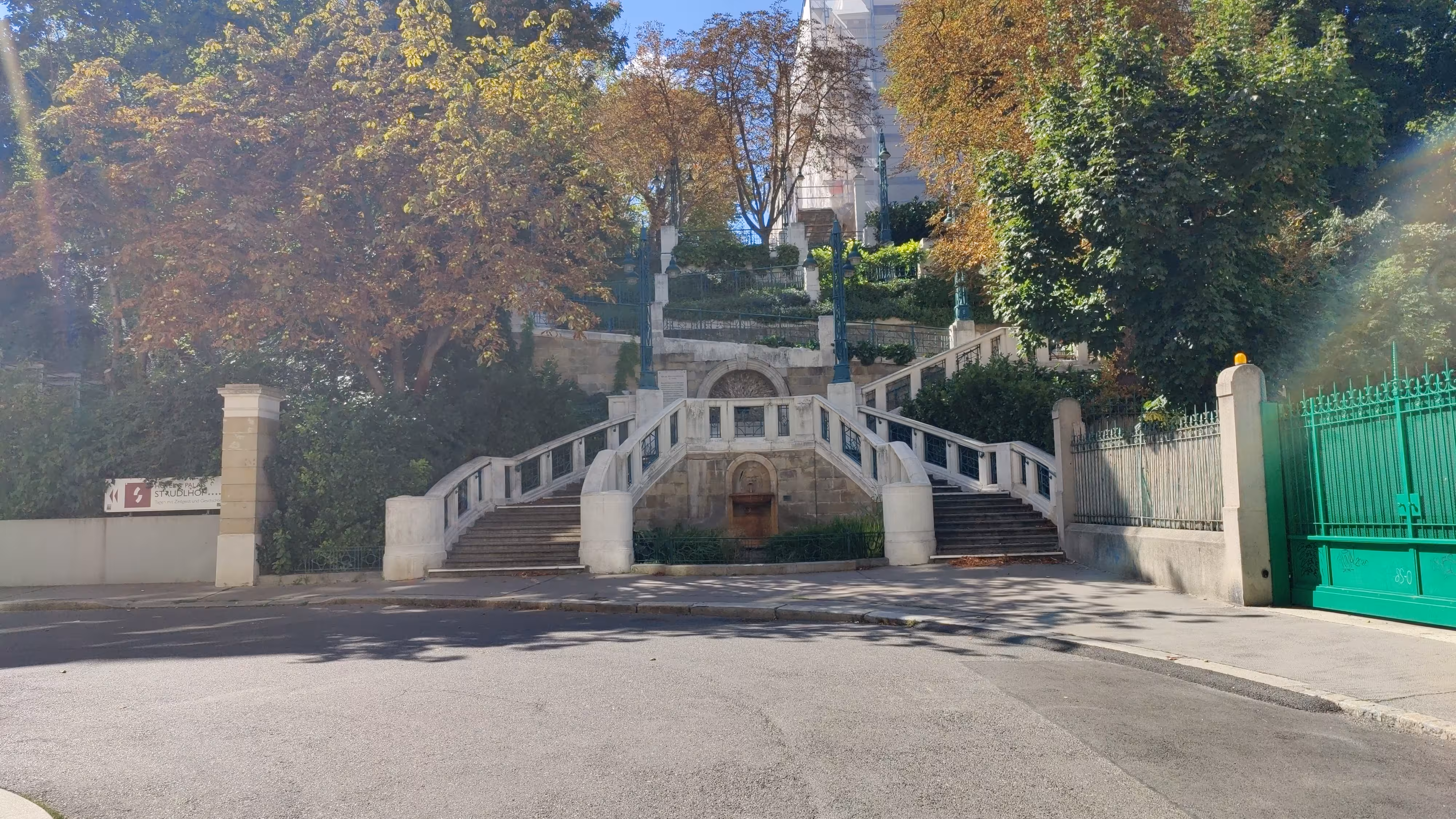 stairs with road in the front and trees in the background. Blue sky can also be seen in the background.
