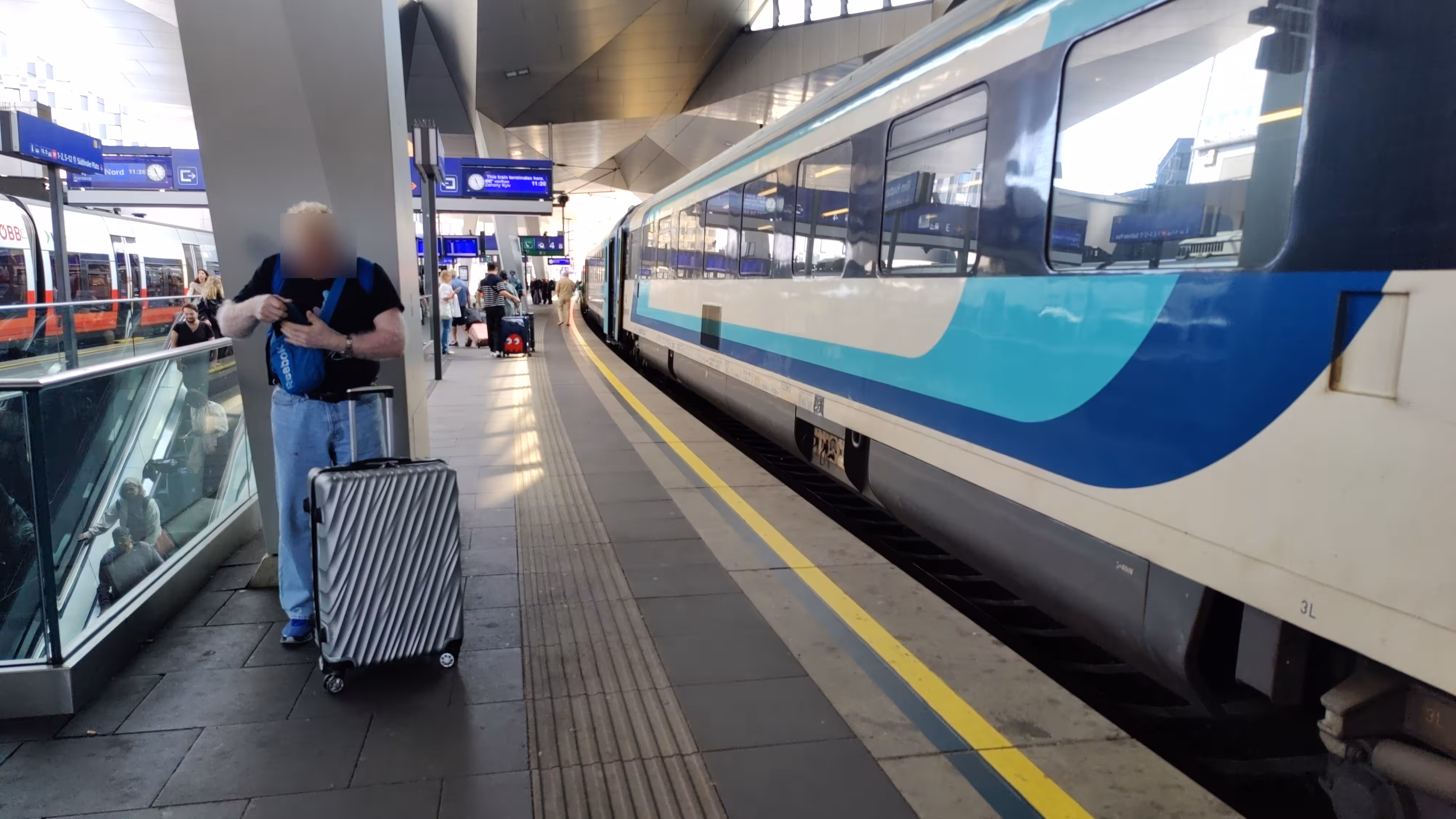 A blue and white colored train on a railway platform